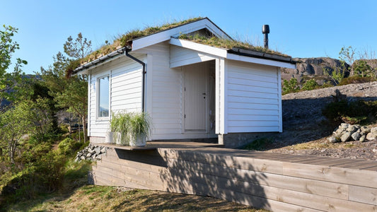 Cozy white guest house with a wooden deck outside.