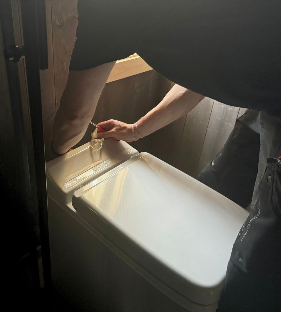 Person installing a Cinderella incineration toilet in a small restroom. 