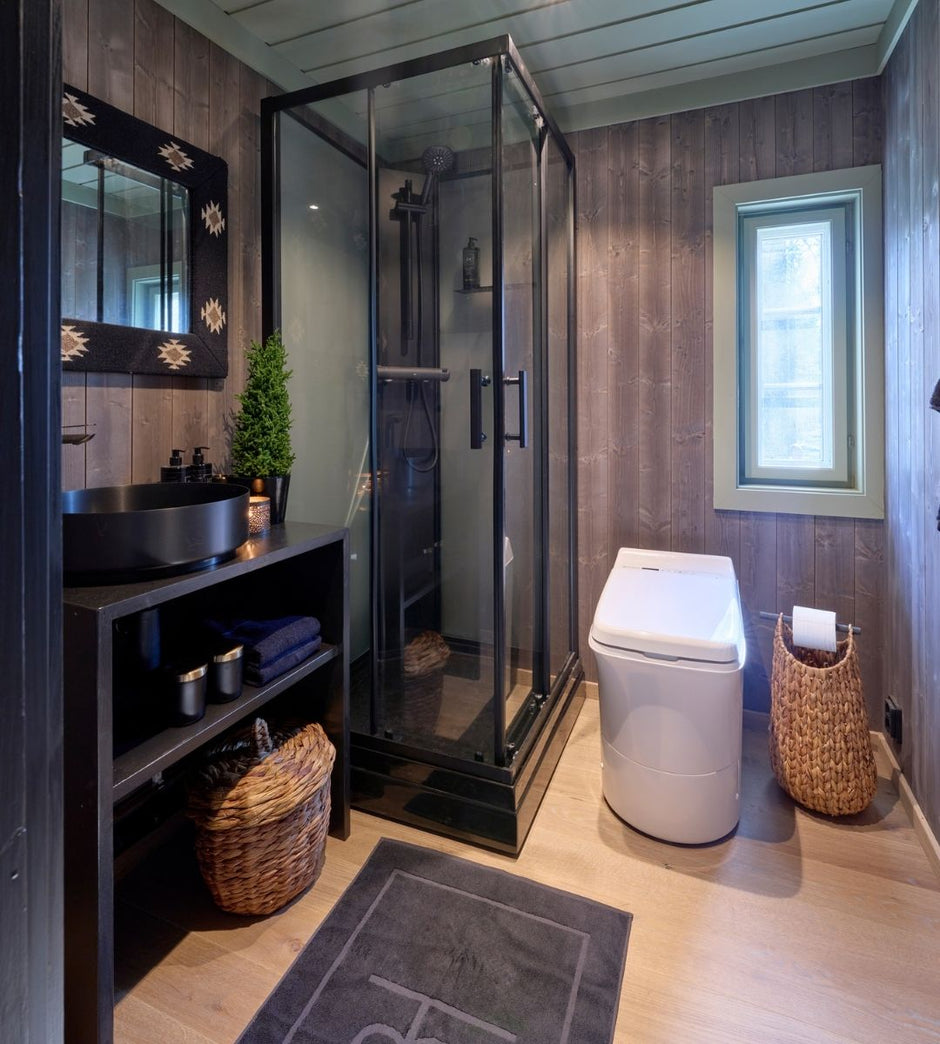 Bathroom with shower, Cinderella incineration toilet, and shelves against wooden walls.