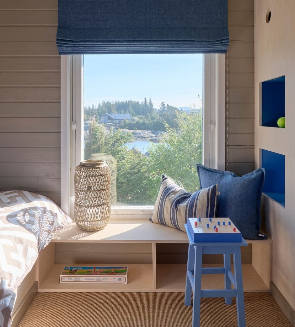 Nook with a window seat, cushions, and a small table with a board game, set against a scenic view.