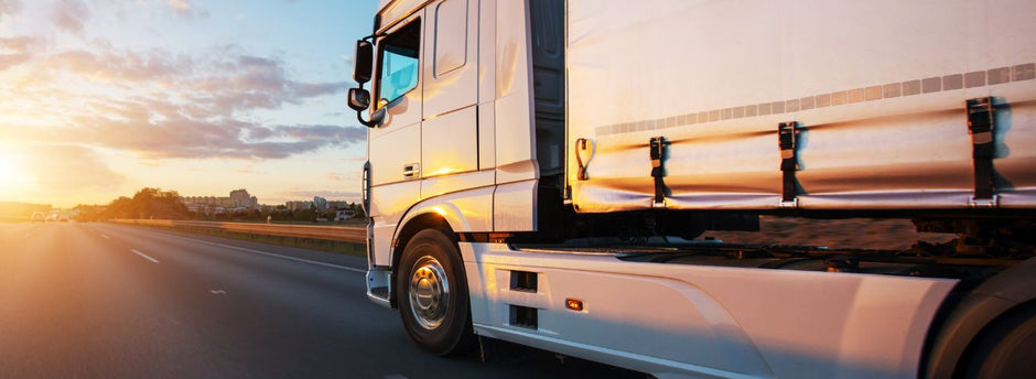 Truck driving on road in sunset