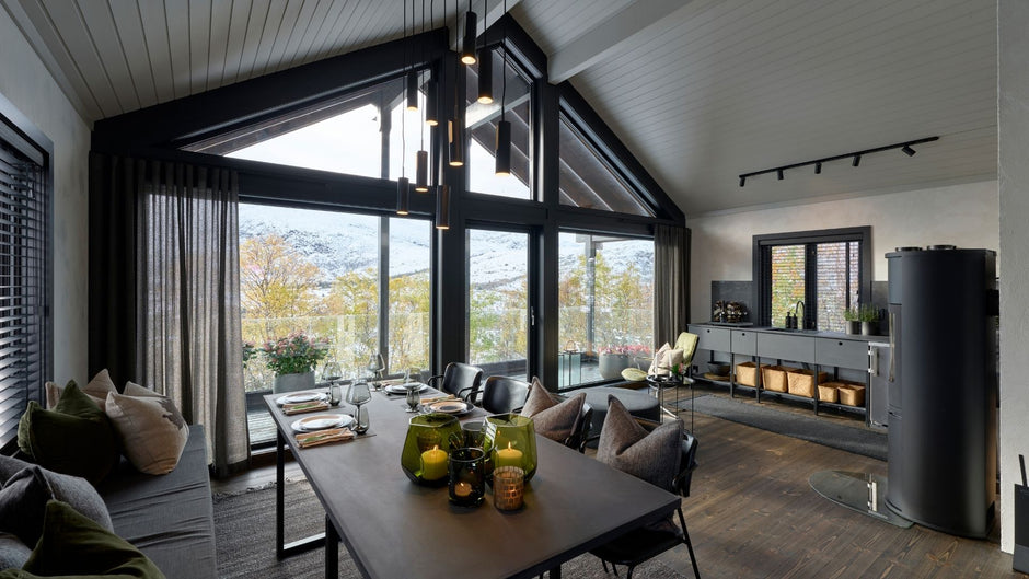 Modernes Wohnzimmer mit großen Fenstern, Möbeln und Dekorationsgegenständen.