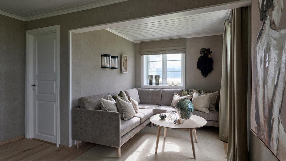 Salón con un cómodo sofá gris, mesa de centro y objetos decorativos.