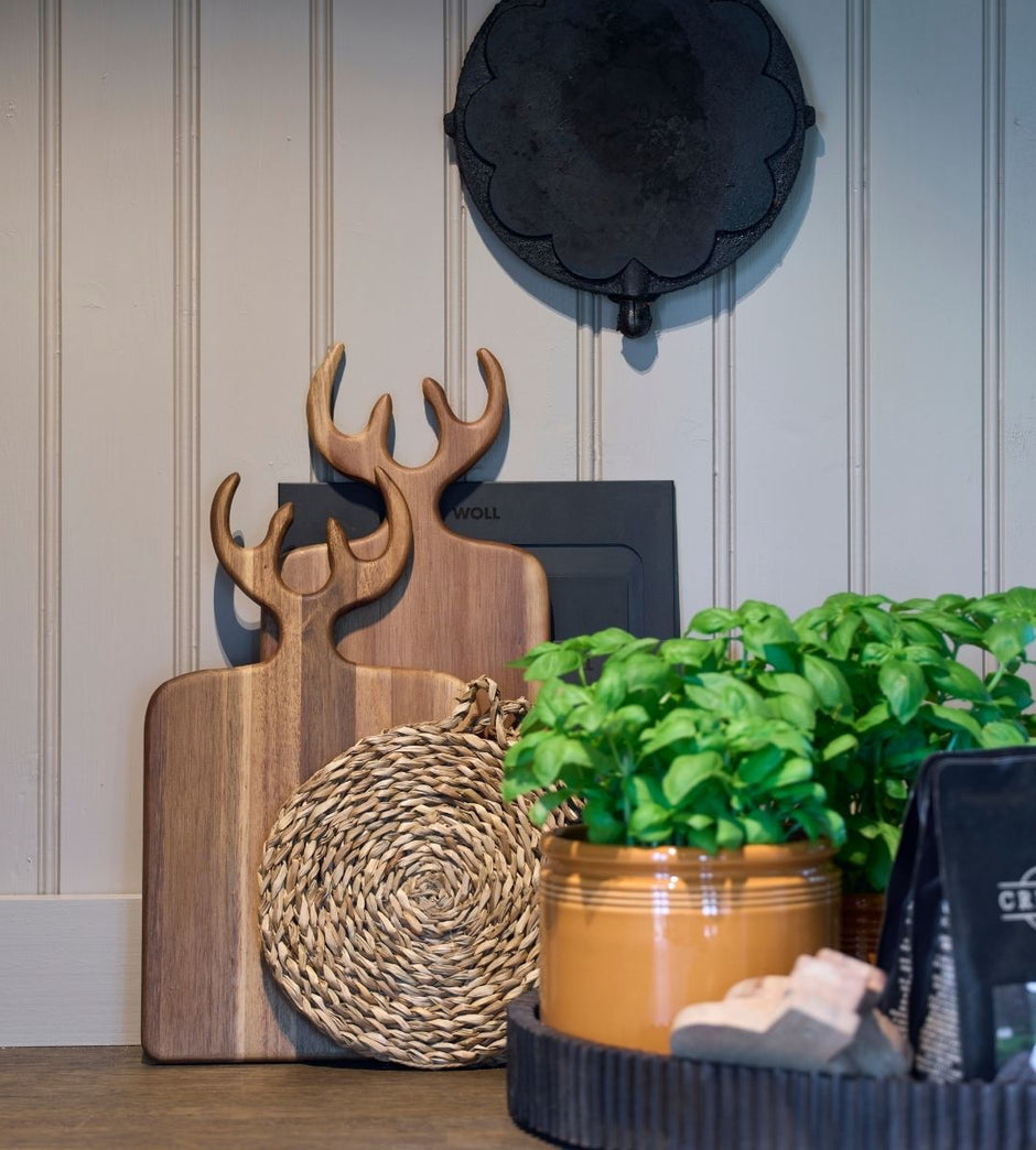 Elementos decorativos como tablas de cortar de madera y una maceta contra la pared.